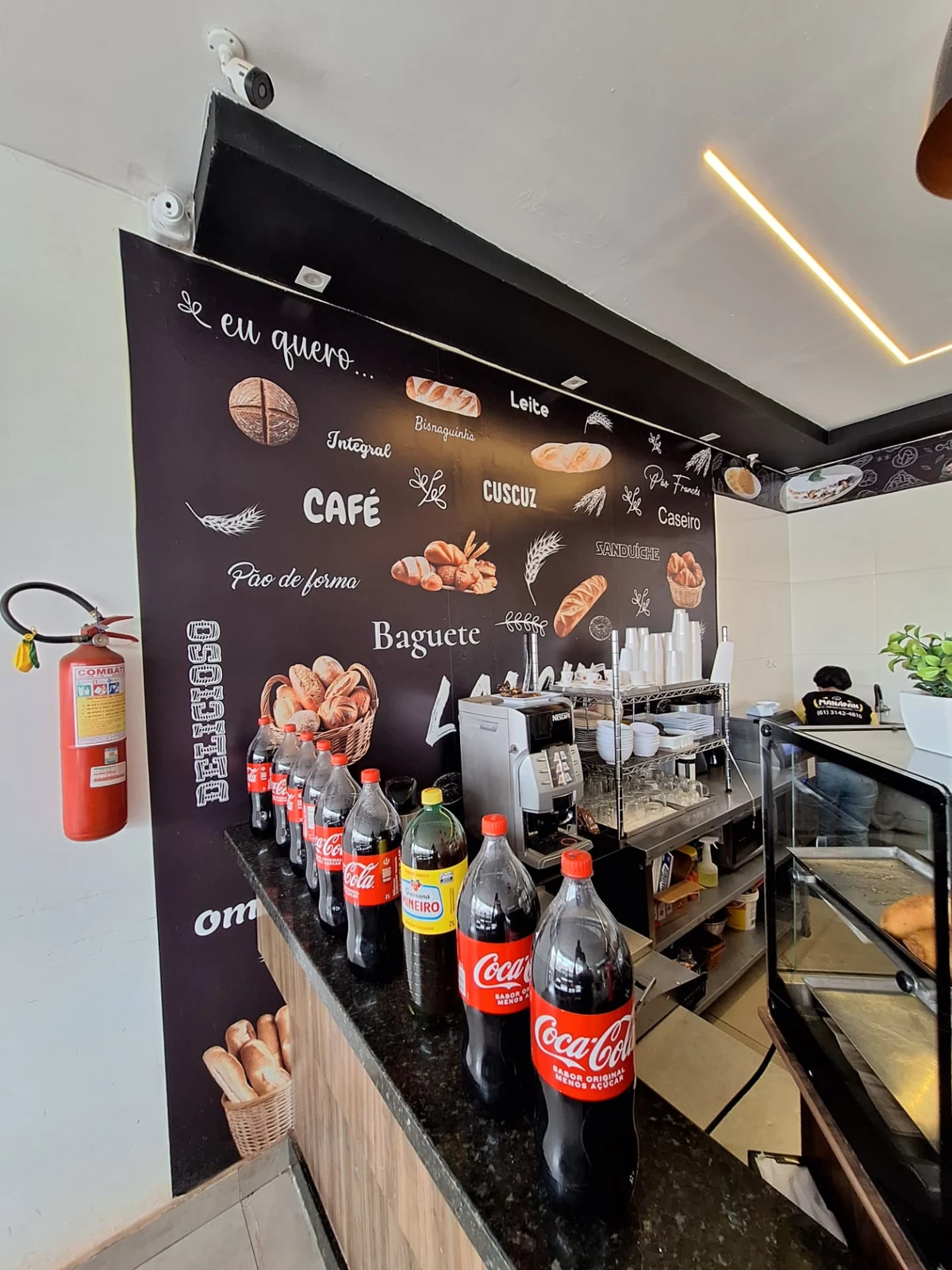 Máquina de café, xícaras e garrafas de refrigerante no balcão da ManáPan